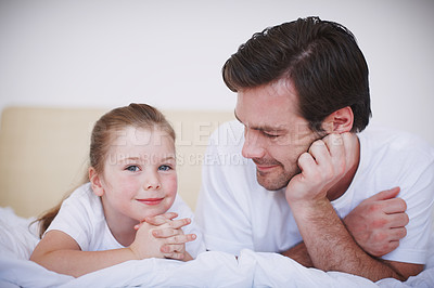 Buy stock photo A father and his young daughter lying side by side on a bed