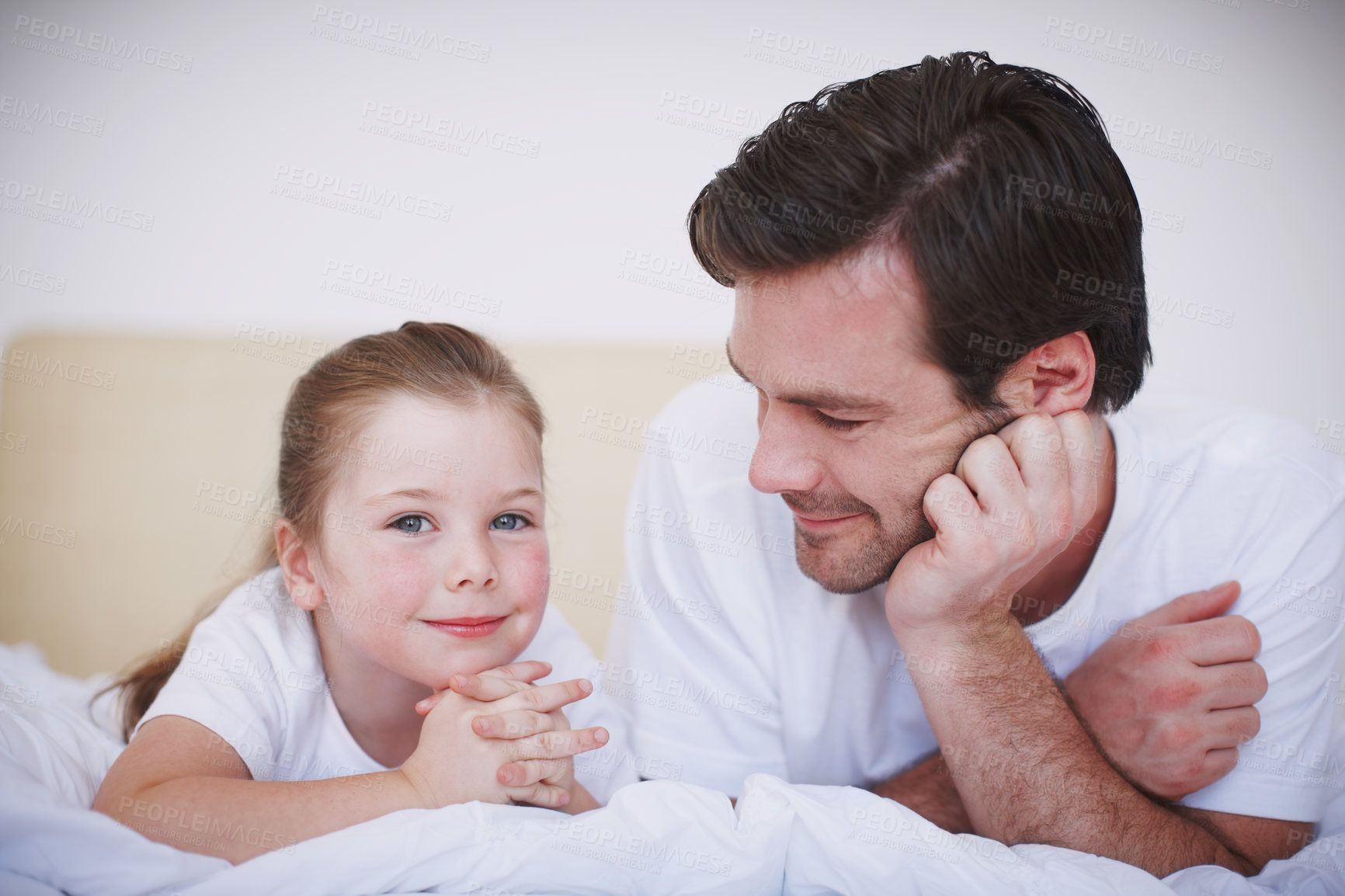 Buy stock photo A father and his young daughter lying side by side on a bed