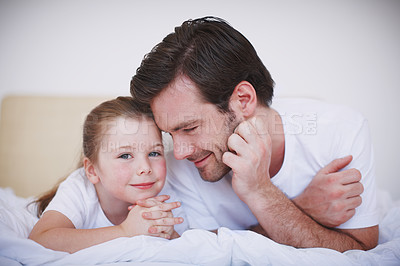 Buy stock photo A father and daughter lying side by side on a bed and showing each other affection