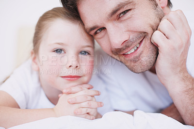 Buy stock photo Cropped shot of a dad and his young daughter lying side by side on a bed
