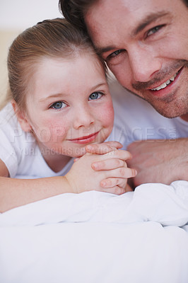 Buy stock photo Cropped shot of a father and daughter lying side by side on a bed
