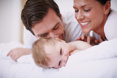 Buy stock photo Two loving young parents showing affection to their  baby girl