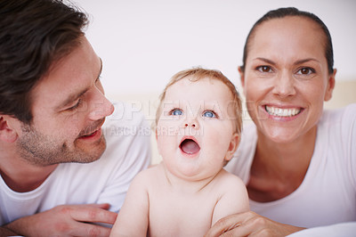 Buy stock photo Two loving young parents and their adorable baby girl lying next to each other