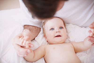 Buy stock photo Shot of a devoted young dad holding onto his baby daughter's hands