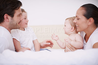 Buy stock photo A close-knit family of four bonding while sitting together on a bed