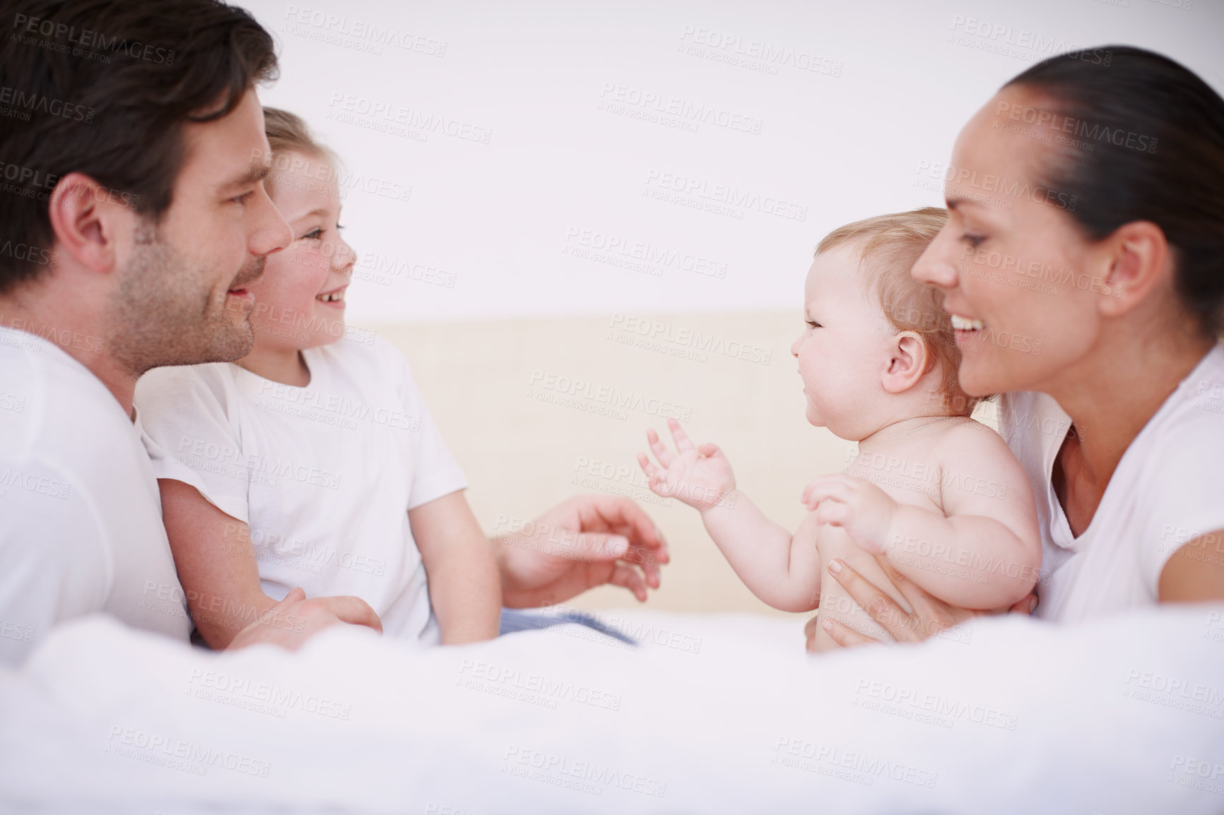 Buy stock photo A close-knit family of four bonding while sitting together on a bed