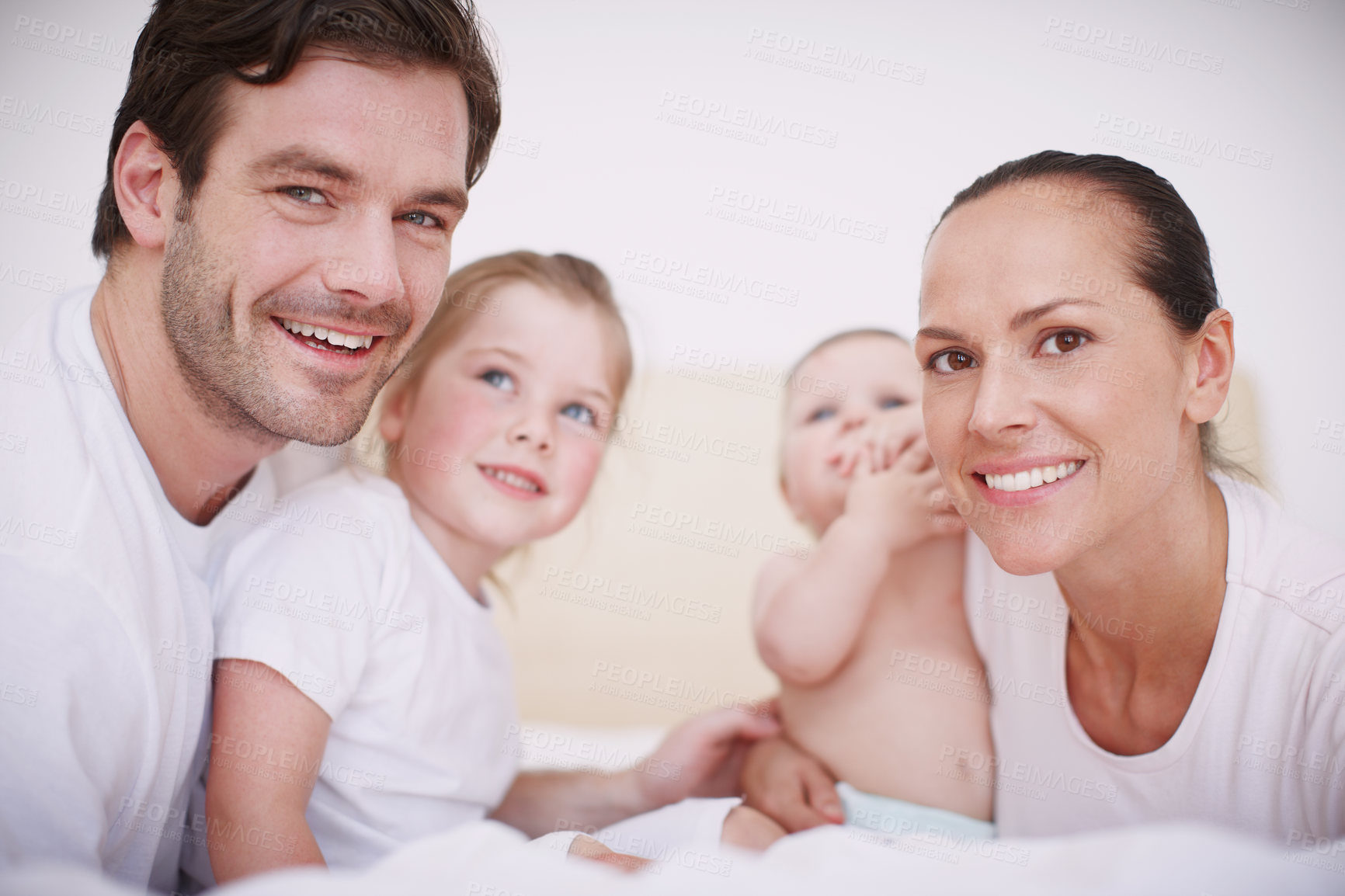 Buy stock photo Shot of a close-knit family of four bonding while sitting together in a bedroom