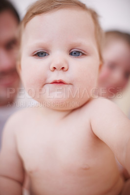 Buy stock photo Closeup shot of an adorable baby girl with her family in the background