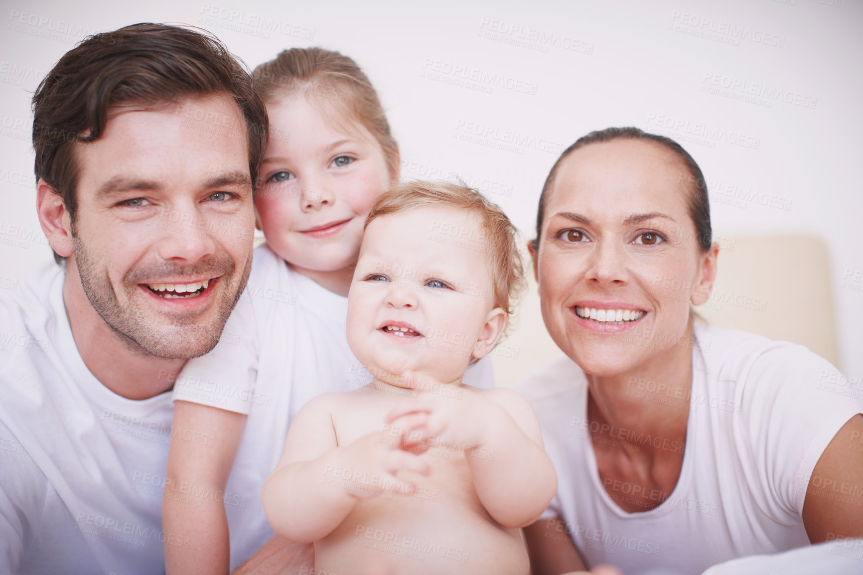 Buy stock photo Cropped portrait of a loving family with two children sitting together in a bedroom