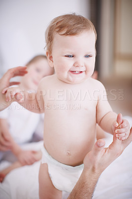 Buy stock photo Cropped shot of a baby girl standing up with the assistance of her parents 