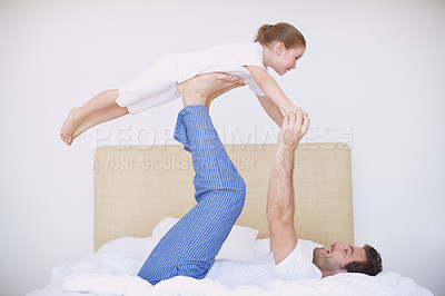 Buy stock photo Side view of a dad playing with his young daughter on a bed