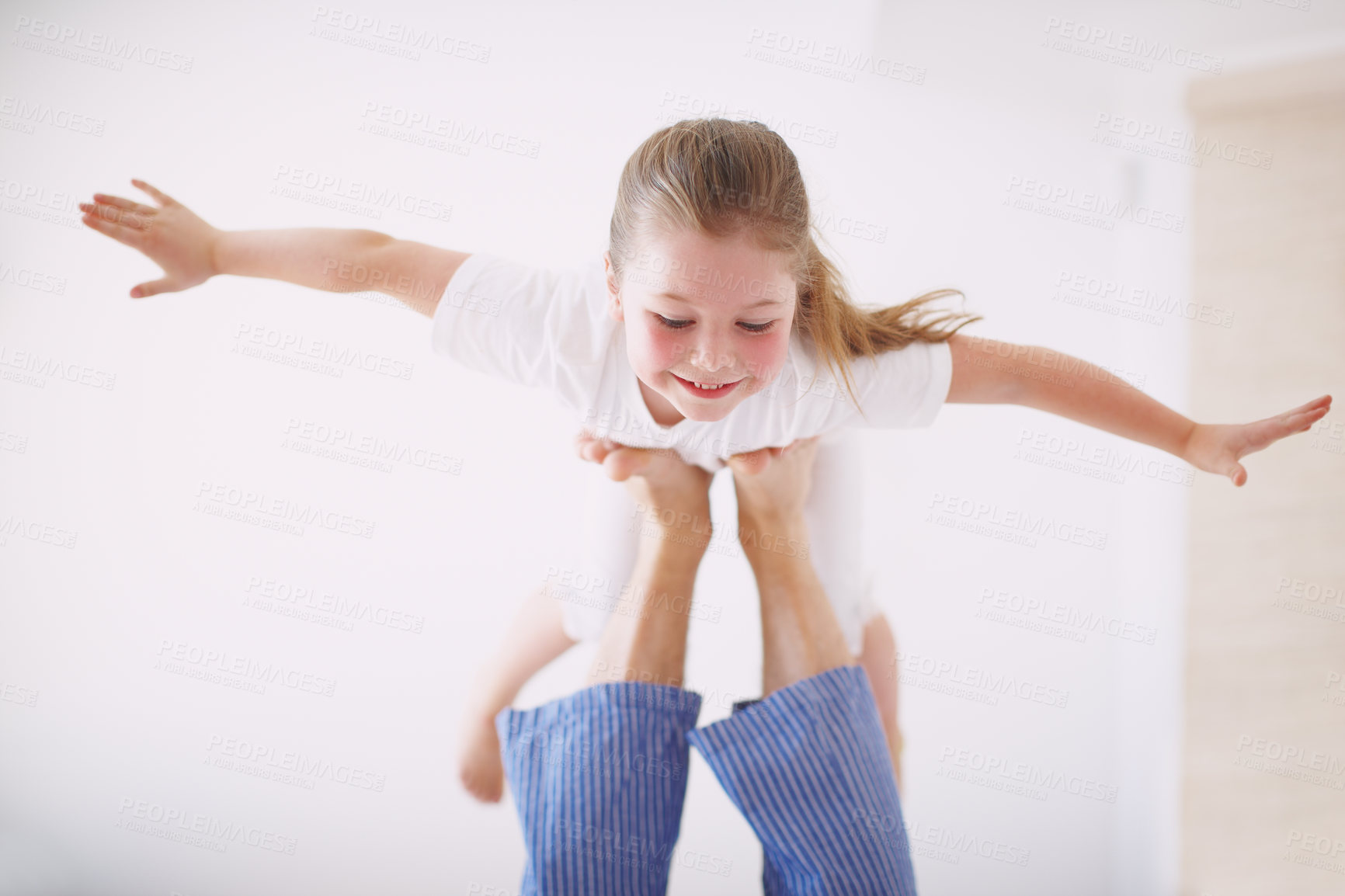 Buy stock photo A young girl propped up on her father's feet with her arms outstretched