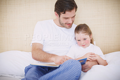 Buy stock photo A devoted father reading his young daughter a bedtime story