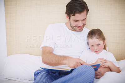 Buy stock photo Shot of a devoted father reading his young daughter a bedtime story
