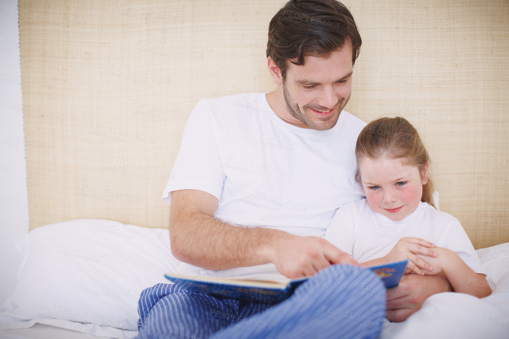 Buy stock photo Shot of a devoted father reading his young daughter a bedtime story