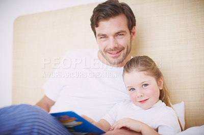 Buy stock photo A devoted father reading his young daughter a bedtime story