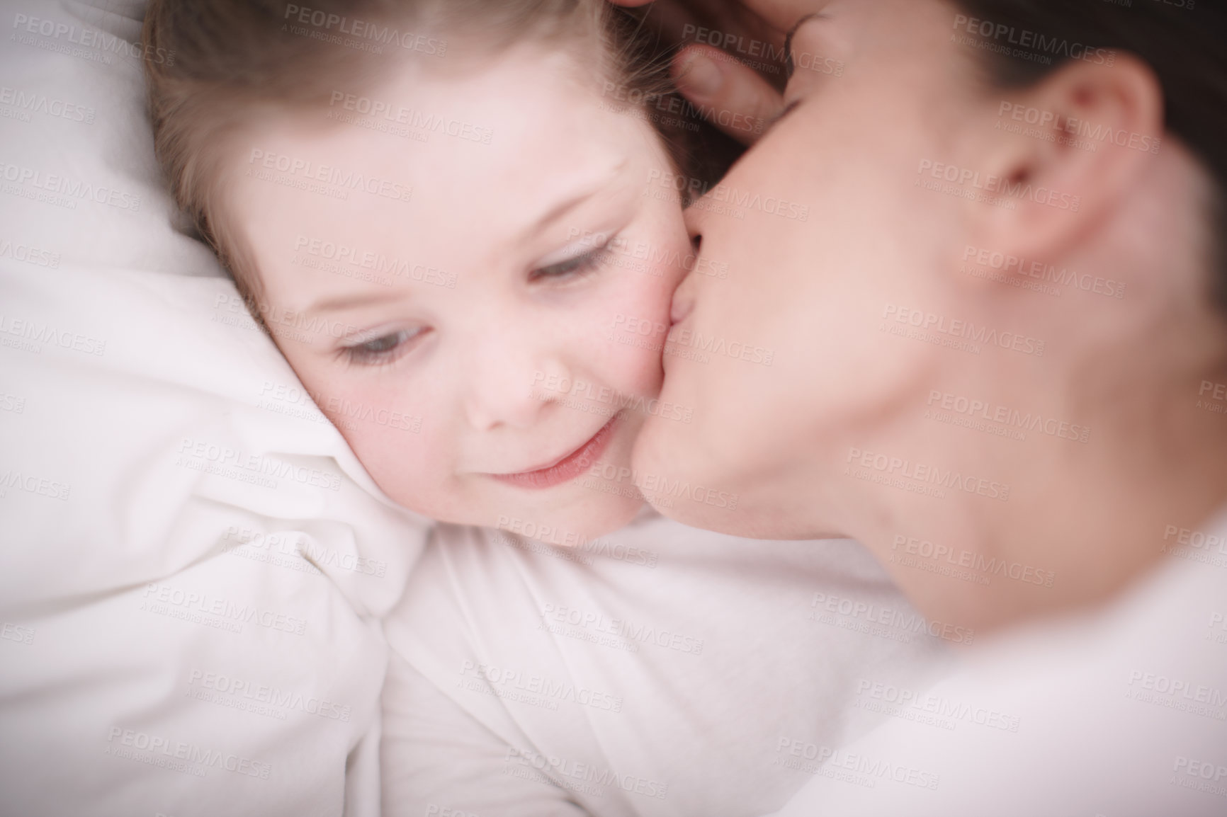 Buy stock photo A mom giving her young daughter a goodnight kiss