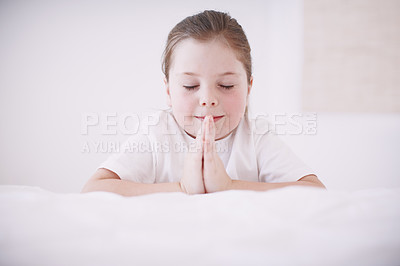 Buy stock photo A young girl kneeling by her bed and saying her prayers 