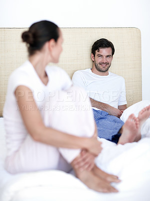 Buy stock photo A young married couple sitting together on their bed