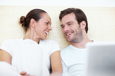 Buy stock photo A young caucasian couple laughing in bed