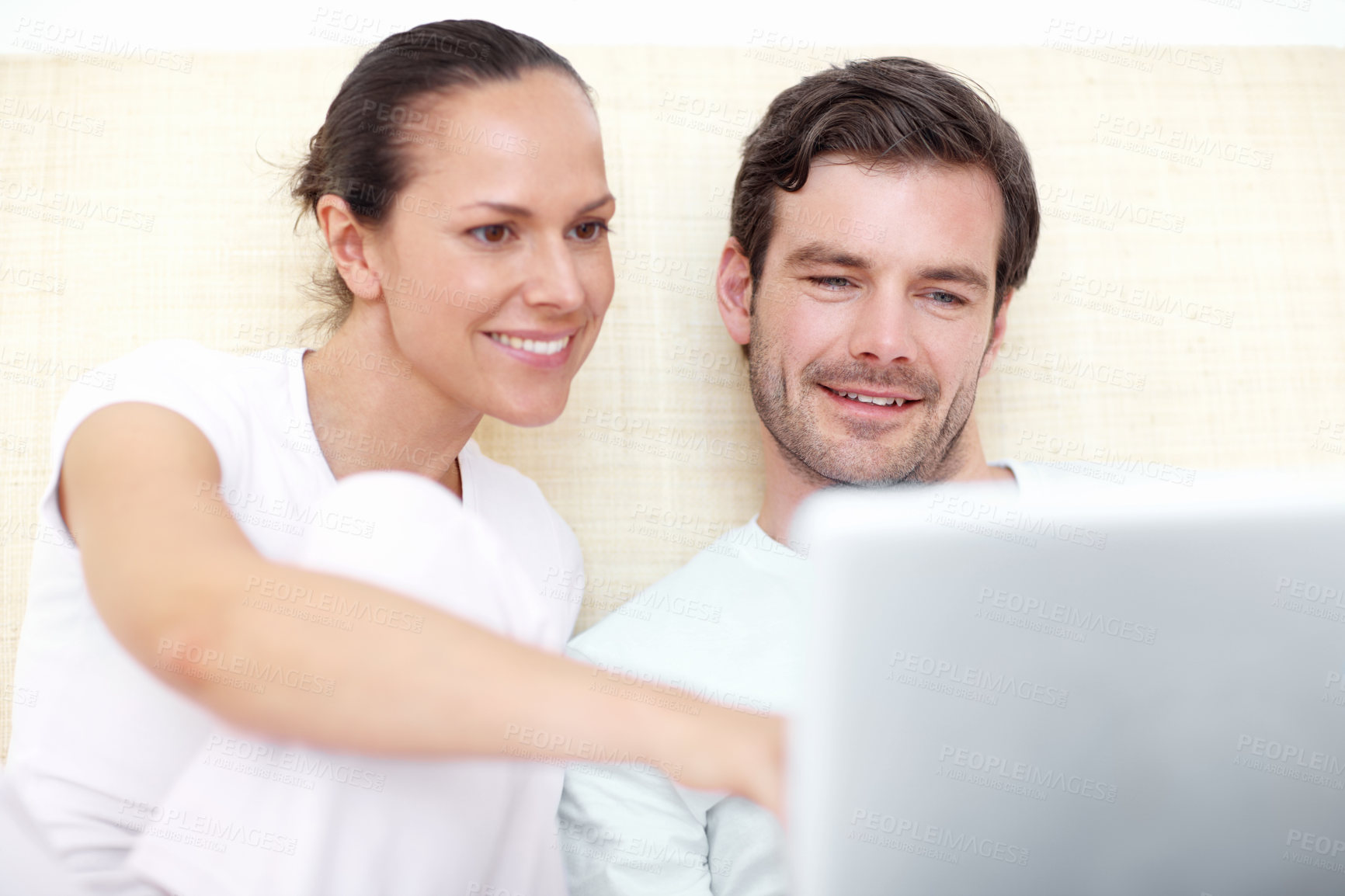 Buy stock photo A young couple working on a laptop in bed