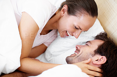 Buy stock photo Shot of a young couple playfully embracing in bed