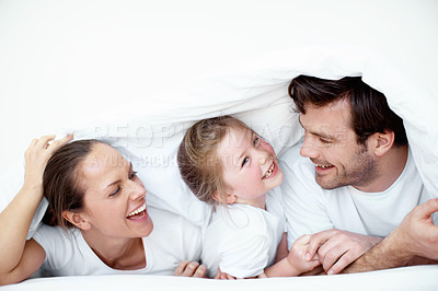 Buy stock photo A young girl playing with her mother and father under bedsheets