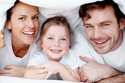 Buy stock photo Portrait of a young family playing underneath the bed covers