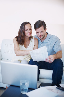 Buy stock photo A young couple discussing their home finances while sitting together in their living room
