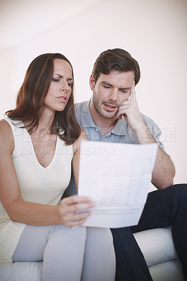 Buy stock photo A married couple having a serious discussion about their home finances while inspecting a bill