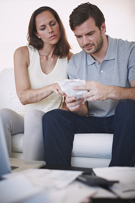 Buy stock photo A married couple having a serious discussion about their home finances while inspecting their bills