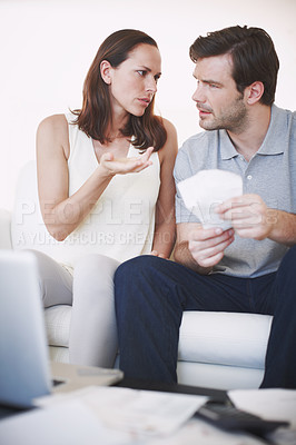 Buy stock photo A married couple looking slightly concerned as they inspect bills and discuss their home finances