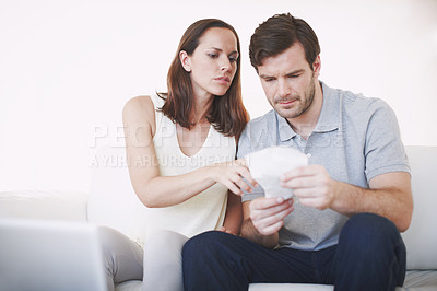 Buy stock photo A married couple looking slightly concerned as they inspect bills and discuss their home finances