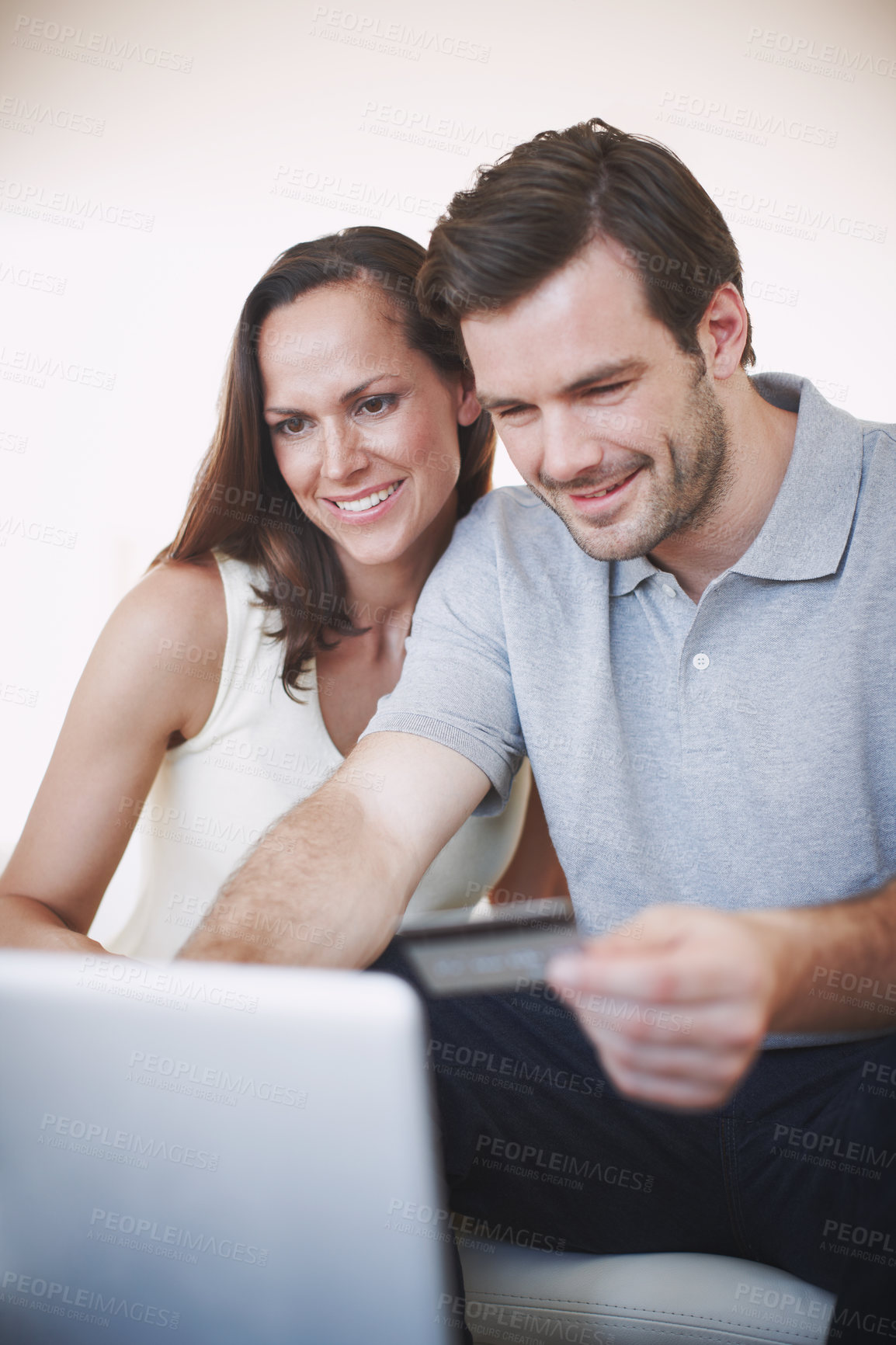 Buy stock photo Shot of a young man doing his banking online while his wife sits beside him