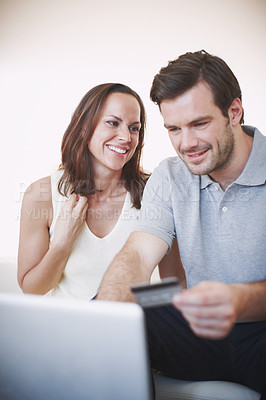 Buy stock photo A young man doing online banking while his wife sits beside him