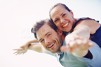 Buy stock photo A handsome man piggybacking his loving wife outdoors