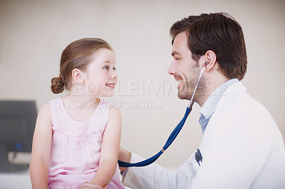 Buy stock photo A male doctor examining a little girl with his stethoscope