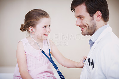 Buy stock photo A little girl reverses roles with her doctor by using his stethoscope on him