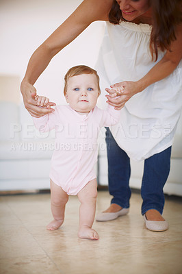 Buy stock photo A mother helping her baby daughter to take her first steps