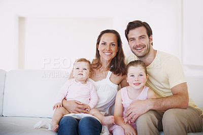 Buy stock photo Portrait of a happy family of four sitting together on a sofa indoors 