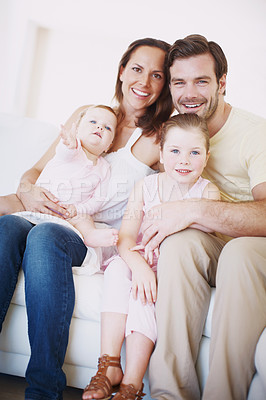 Buy stock photo Closeup portrait of a family with two children sitting together on a sofa indoors 