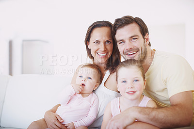Buy stock photo Cropped portrait of a happy family of four sitting close together on a sofa indoors 