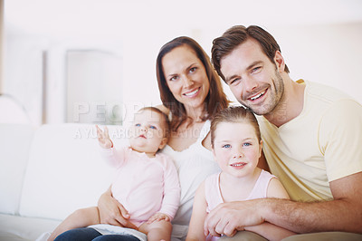Buy stock photo Portrait of a beautiful family of four sitting together on a sofa indoors