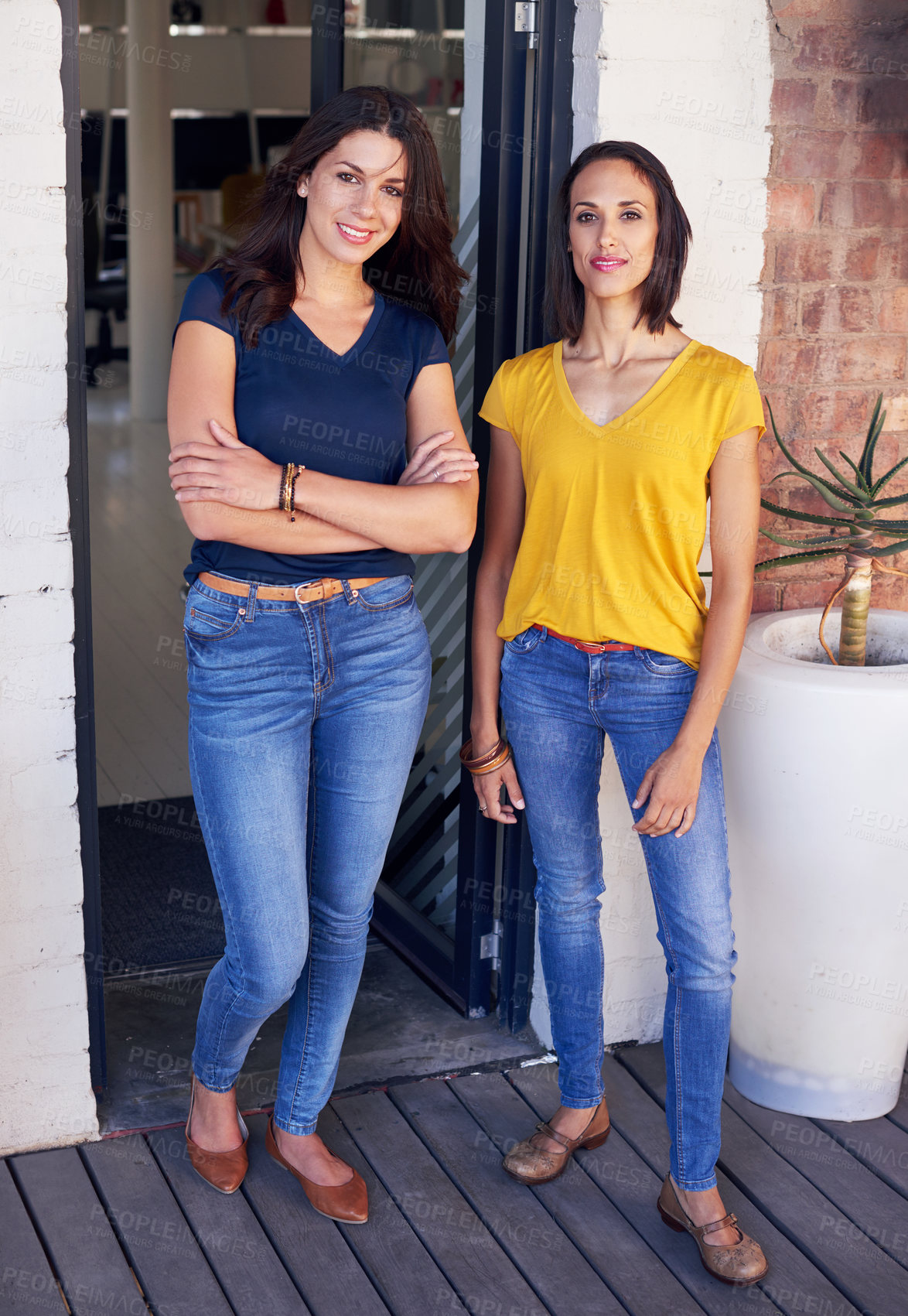 Buy stock photo Two young women standing in front of their workplace