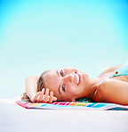 Happy female lying in bikini on a towel against blue