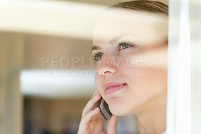 Buy stock photo Young woman having a conversation over the cellphone , view through a glass
