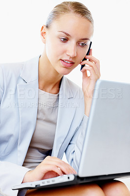 Buy stock photo Pretty young business woman using a laptop and speaking on the cellphone