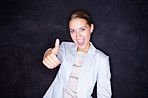 Happy business woman gesturing a success sign against black