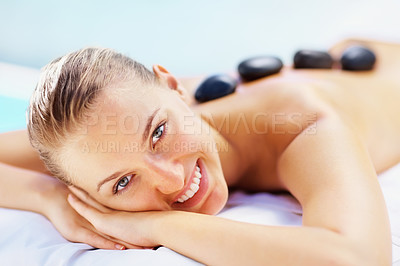 Buy stock photo Portrait, spa bed and happy woman with hot stone back massage, relax or stress relief body treatment at wellness resort. Luxury, zen and face of female person at salon for healing, therapy or pamper