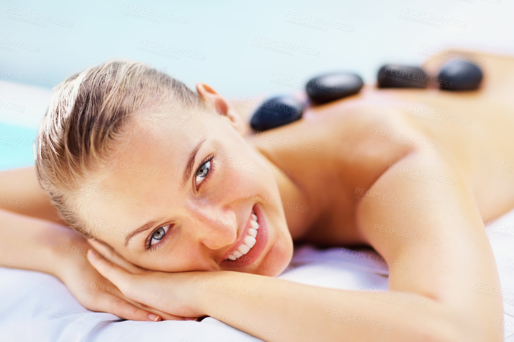 Buy stock photo Portrait, spa bed and happy woman with hot stone back massage, relax or stress relief body treatment at wellness resort. Luxury, zen and face of female person at salon for healing, therapy or pamper